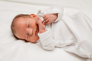 baby laying on bed at a newborn session by Alexandra Szebenyik photography