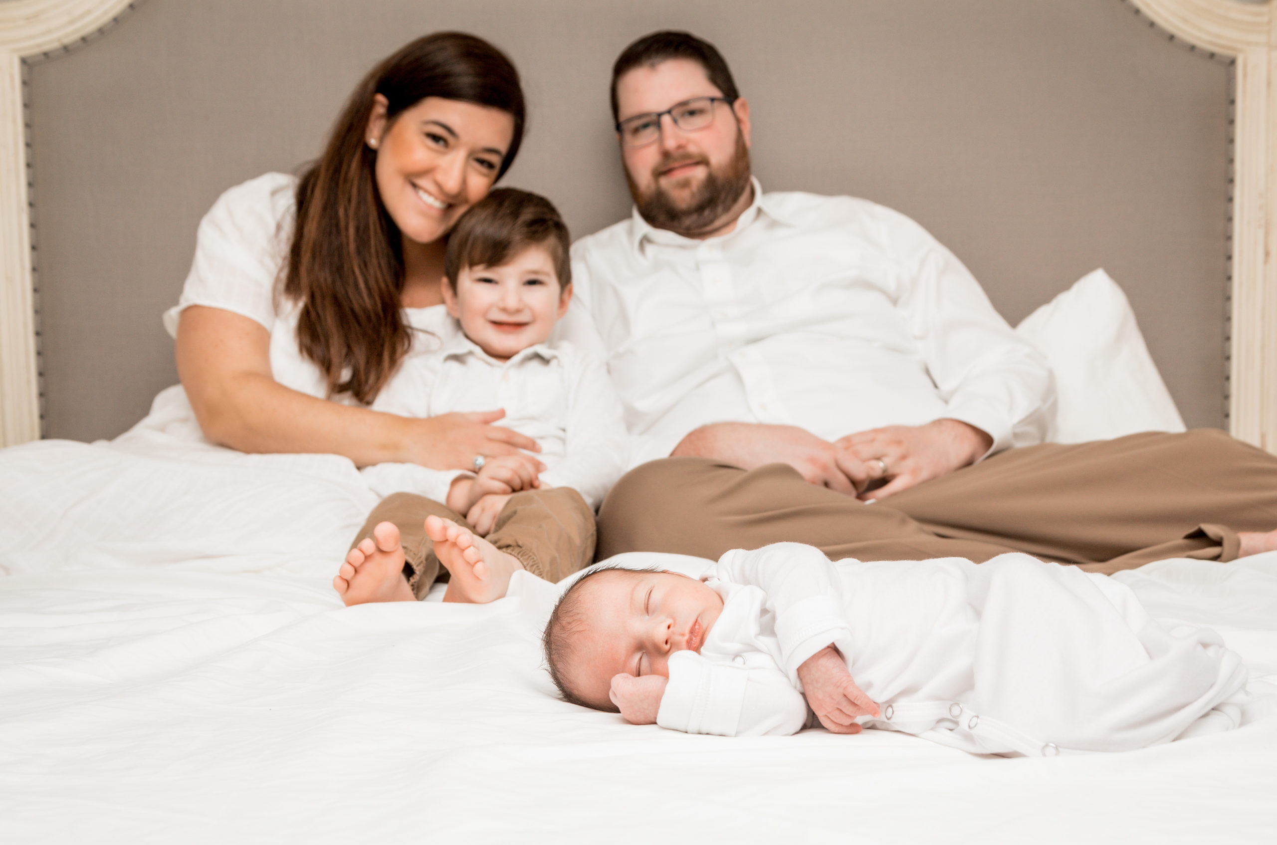family laying on bed at their lifestyle newborn photoshoot with Alexandra Szebenyik Photography